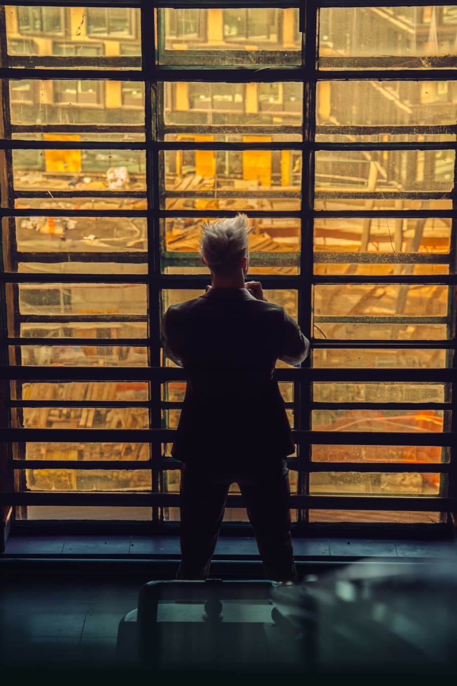 Manuel Stierberger von hinten vor einem Fenster, dahinter eine Baustelle im Abendlicht